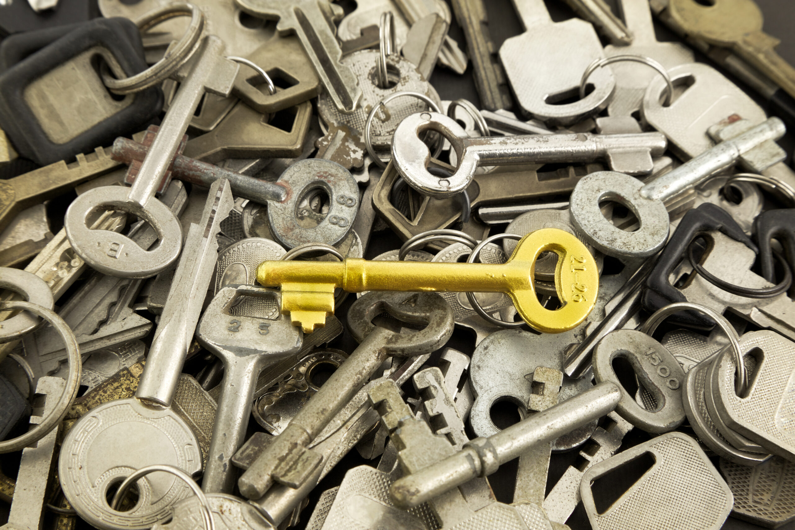 Gold skeleton key atop a pile of silver keys