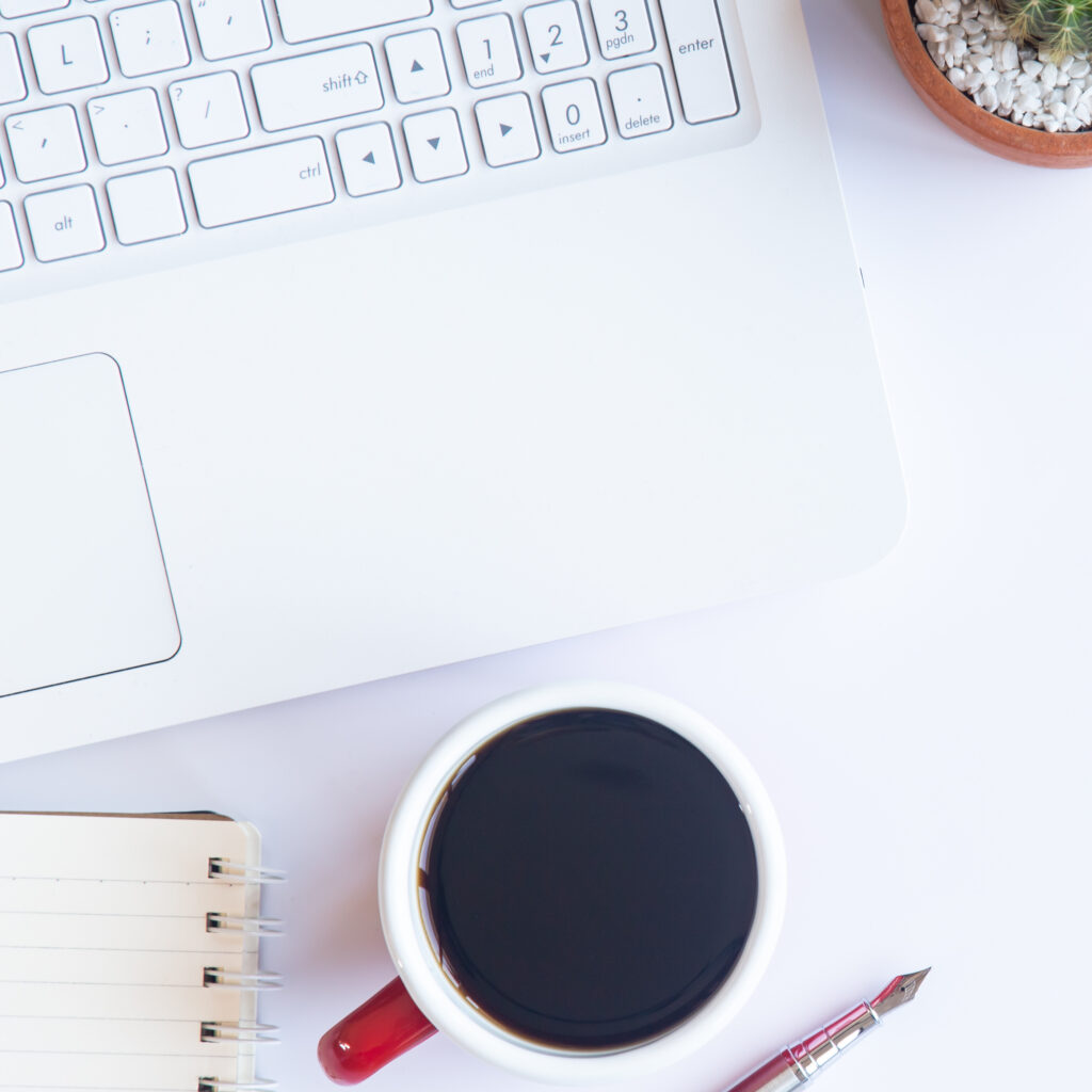 White desk office with laptop, smartphone and other work supplies with cup of coffee. Top view with copy space for input the text. Designer workspace on desk table essential elements on flat lay.